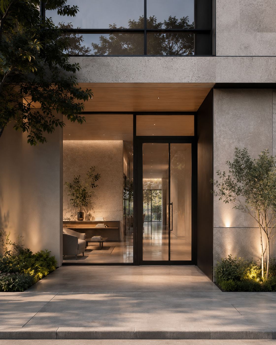 Entrada de uma residência ao anoitecer: portal de vidro e madeira entre paredes de concreto, iluminação embutida quente e vegetação nas laterais.